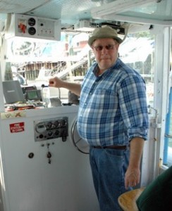 Tour boating captain in blue shirt standing at the helm of his boat