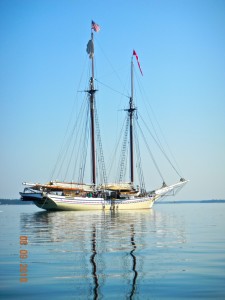 beautiful yellow schooner at anchor on a calm sea w/ blue sky behind