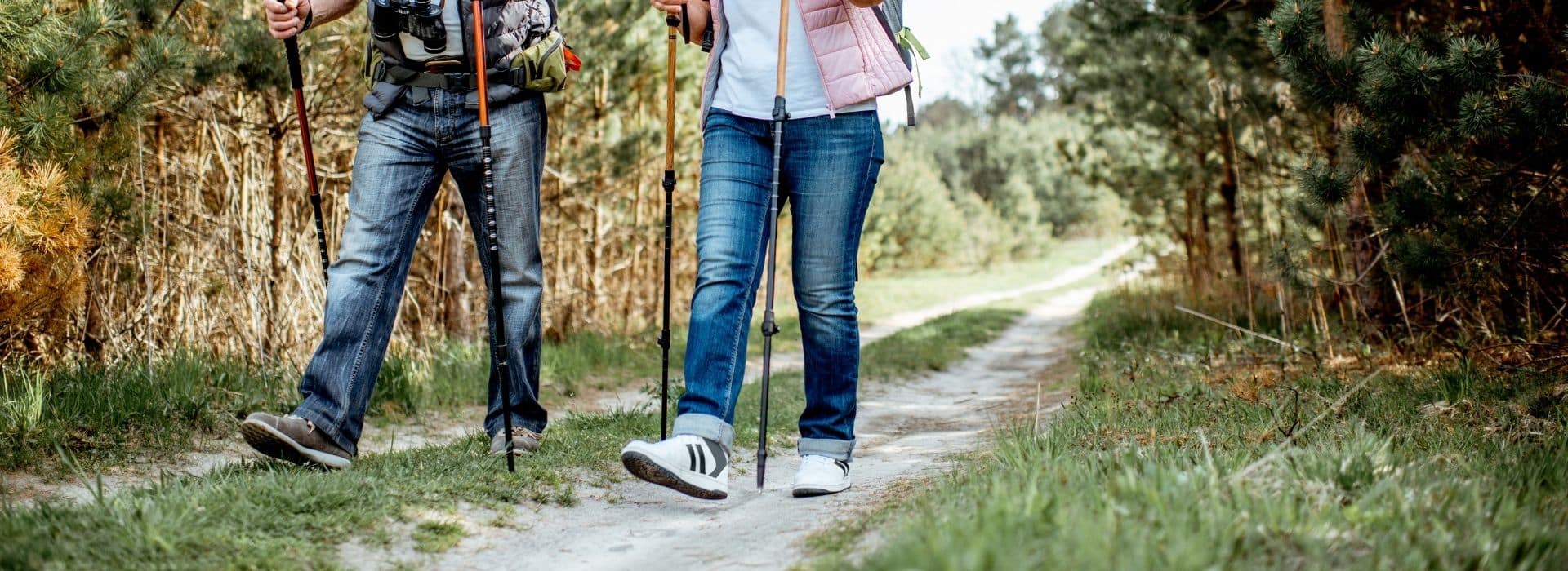  a couple hiking on a trail with hiking poles