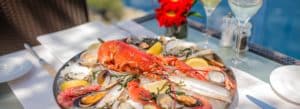 A plate of lobster, clams, lemon wedges, with drinks on the side