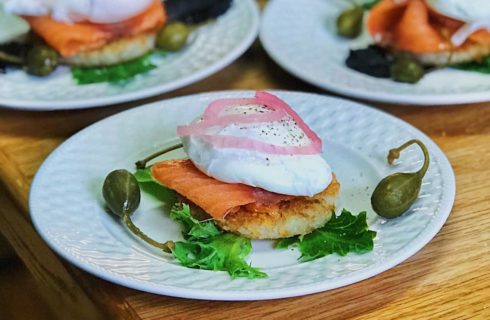 Close up view of a lunch dish with smoked salmon, sour cream, and a hashbrown on white plate