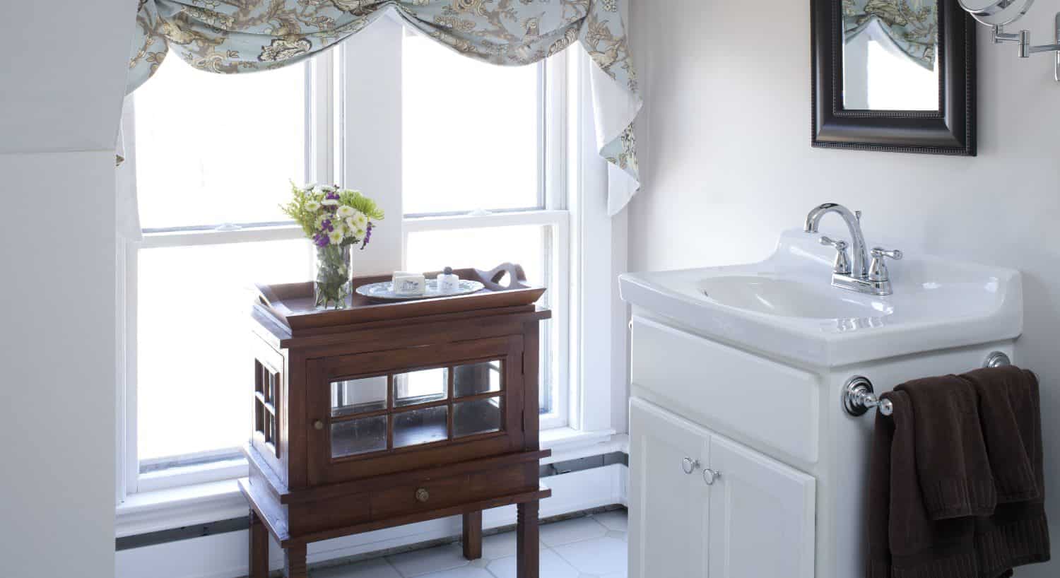 Bathroom with light colored walls, white trim, dark wooden table, white sink, and white vanity