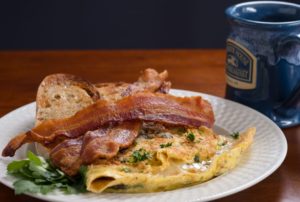 Close up view of an egg breakfast dish with bacon on white plate